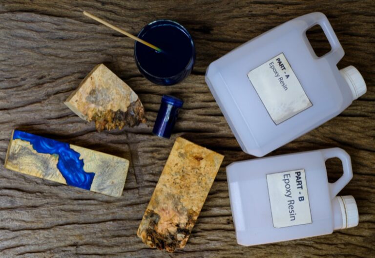 Various epoxy resin casts alongside containers of resin and hardener on a wooden surface.