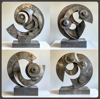 Four abstract metal sculptures with circular and spiral shapes displayed on individual pedestals against a plain background.