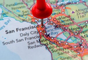 A red pushpin marks San Francisco on a detailed road map, highlighting surrounding cities and road networks.
