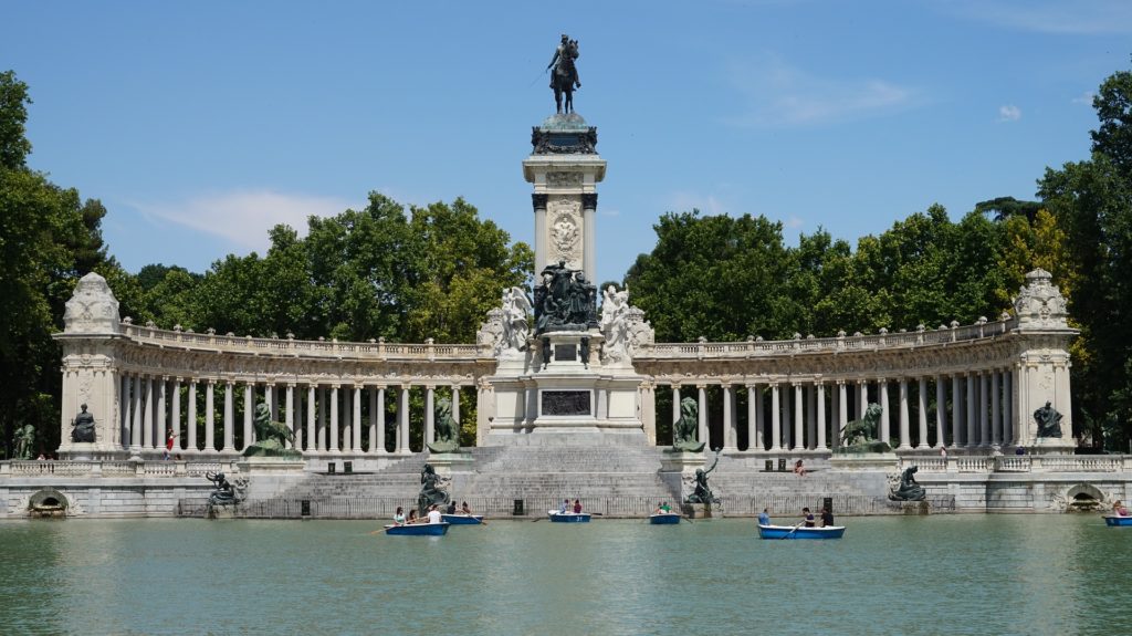 Gente en barcas de remos delante de un gran monumento en españa