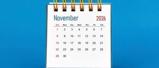 A desk calendar shows the month of November 2026 with dates arranged in a grid, set against a plain blue background—marking a year since the hemp bill November 2025 shaped new hemp compliance for 2026.