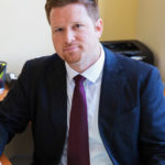 A man in a suit sitting at a desk.