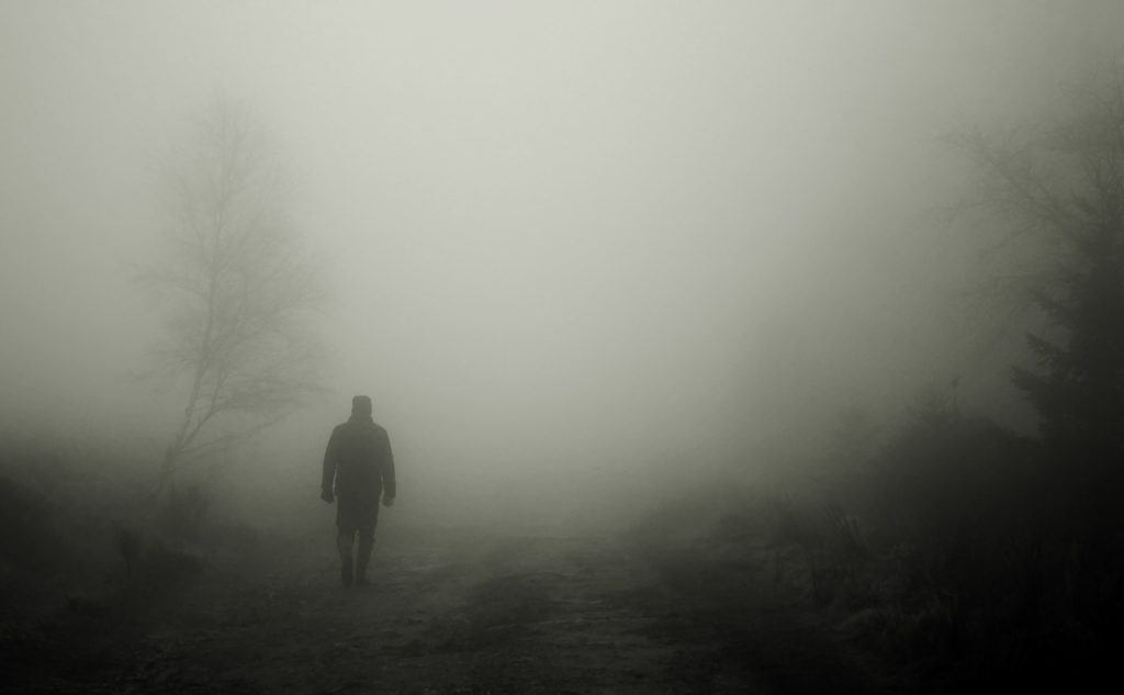 BW photo of man walking through fog