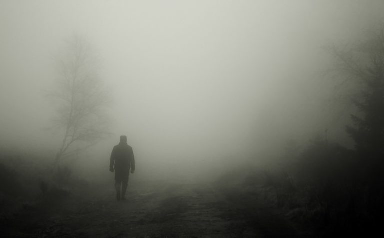 Fotografía en blanco y negro de un hombre caminando entre la niebla